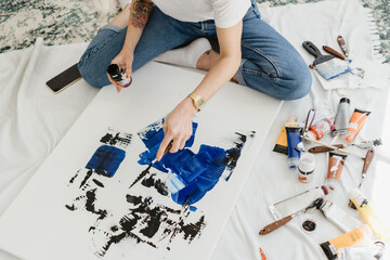Woman's hand drawing on white canvas using phantom blue and black oil colors. Many drawing...