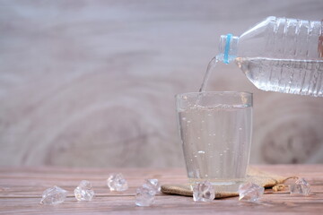 Pouring drinking water in glasses on wood table background and space for text