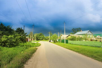Fototapeta na wymiar village road, forest and sky in clouds