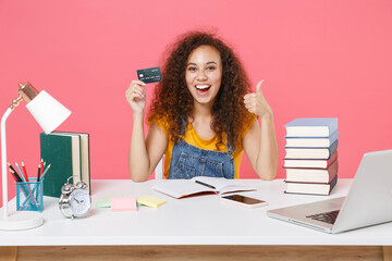 Excited african american girl employee in office sit isolated on pink background. Achievement...