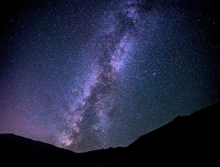 Landscape of the starry sky, in the middle of the frame is the Milky Way. Night sky with stars and silhouettes of mountain hills.