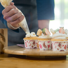 Asian teenager boy decorating cupcakes at home, lifestyle concept.