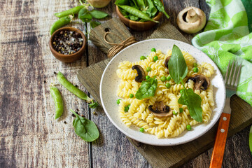 Healthy food. Homemade Pasta fusilli with green peas and grilled champignons on a wooden table.  Copy space.