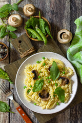 Healthy food. Homemade Pasta fusilli with green peas and grilled champignons on a wooden table. Top view flat lay background.