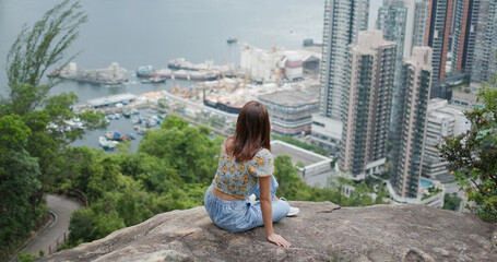 Fototapeta na wymiar Woman sit at the top of the hill and enjoy the city view