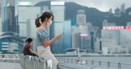 Woman wear face mask and use of mobile phone in Hong Kong
