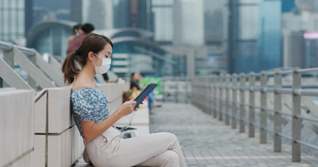 Woman wear face mask use of tablet computer at outdoor