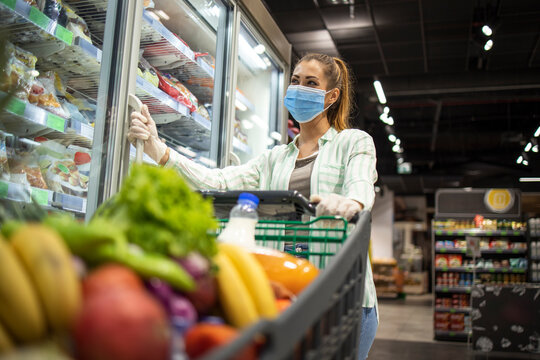 Woman with protective mask and gloves shopping in supermarket during COVID-19 pandemic or corona virus. Protect yourself against highly contagious coronavirus.