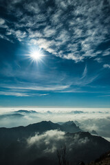 Fototapeta premium Vertical landscape of mountains, clouds, sun and sky