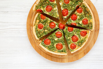 Homemade Spinach Quiche on a round bamboo board, top view. Flat lay, overhead, from above. Space for text.