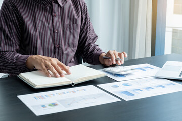 The hands of a male businessman are analyzing and calculating the annual income and expenses in a...