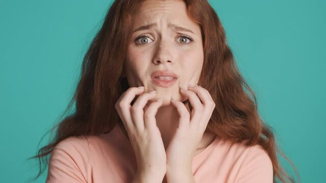 Close up scared redhead girl fearfully looking around over colorful background. Scared expression