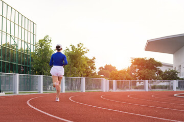 Obraz premium Young fitness woman runner jogging excercise in the morning on city stadium track in the city. Female athlete excercise in the city stadium to keep body fitness. Health and recreation stock photo.
