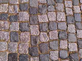 Stone road is grey. The background of the granite cobblestone pavement. Abstract background of the old cobblestone pavement. Texture