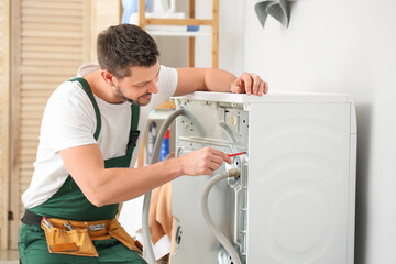 Worker repairing washing machine in laundry room