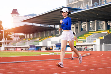Obraz premium Young fitness woman runner jogging excercise in the morning on city stadium track in the city. Female athlete excercise in the city stadium to keep body fitness. Health and recreation stock photo.