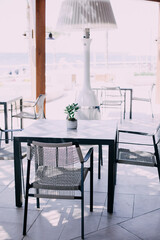 Black square table with designer chairs against the background of the sea. Outdoor cafe terrace
