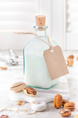 Vegan nut milk from pecan in glass bottle. High key