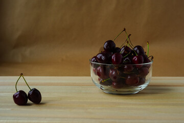 Bowl with sweet cherry on a wooden table