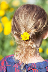 Naklejka premium Yellow flower in children's hair.