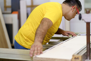 Busy skilled masterful experienced carpenter taking measurements to create furniture. Concept of DIY woodwork and furniture making.
