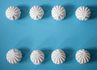 Frame on a blue background of eight white marshmallows: delicious sweet background, space for text