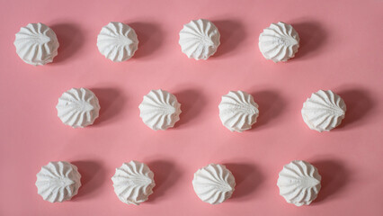 Twelve large white marshmallows diagonally apart on a pink background: delicious sweet background, seamless pattern