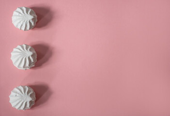 Three white large and delicious hand-made marshmallows lie vertically above each other on a pink background: sweet background, seamless pattern, space for text