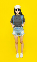 Traveler tourist beautiful young asian woman in casual clothes and sunglasses with Backpack Selfie isolated on yellow background.Summer holidays, vacation and travel concept
