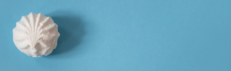 Fototapeta premium One large white marshmallow on a blue banner: delicious sweet background, space for text