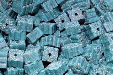 Gloved hand holding blue rodent poison.These dry poison blocks can be placed in areas where rodents...