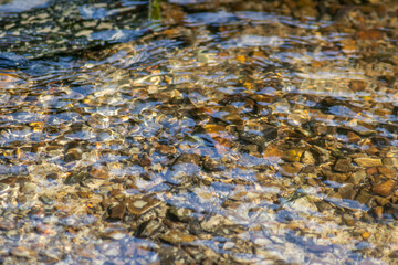 Silky ripples in water of a crystal clear water creek as idyllic natural background with high angle view shows zen meditation and little waves in a healthy mountain spring with a clear floating stream