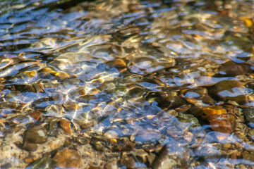 Silky ripples in water of a crystal clear water creek as idyllic natural background with high angle view shows zen meditation and little waves in a healthy mountain spring with a clear floating stream