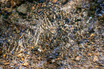 Silky ripples in water of a crystal clear water creek as idyllic natural background with high angle view shows zen meditation and little waves in a healthy mountain spring with a clear floating stream