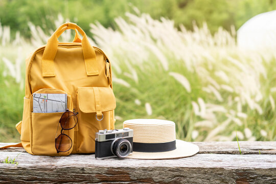 Travel backpack with traveler items on wooden bench with nature background and copy space