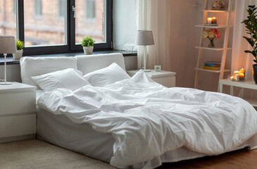 Fototapeta na wymiar coziness and interior concept - cozy bedroom with white linen on bed