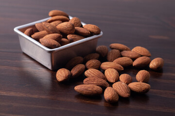 Almonds in a zinc cup on a wooden floor