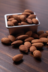 Almonds in a zinc cup on a wooden floor