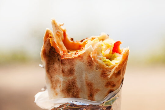 a roll pizza with vegetables that someone took a few pieces from