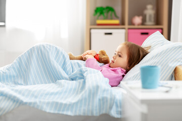 health, children and people concept - sick little girl lying in bed at home