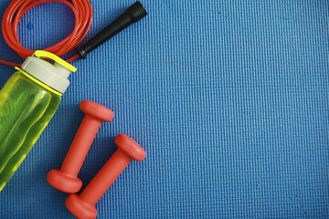 Sport and healthy lifestyle. Accessories for sports. Yoga mat dumbbell and jump rope. Sports background home exercises concept.