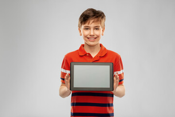 technology, communication and people concept - happy smiling boy in red polo t-shirt showing tablet...