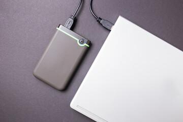 Hard disk and laptop on a black table close-up.