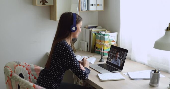 Woman sit at desk wear headphones looks at pc screen talking with teacher distantly by video call, Online tutoring language teaching, colleagues work on common project use video conference app concept