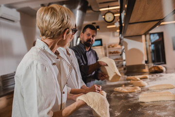 Fototapeta na wymiar Group of bakers examine quality of dough for baking bread in modern manufacturing.