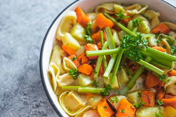 plant-based food, vegan ravioli pasta with vegetable broth topped with pumpkin and sweet potato cubes and celeri sticks