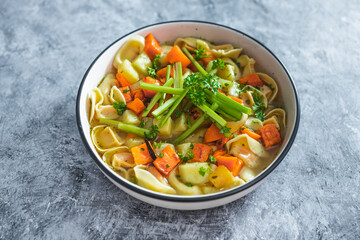 plant-based food, vegan ravioli pasta with vegetable broth topped with pumpkin and sweet potato cubes and celeri sticks