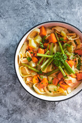 plant-based food, vegan ravioli pasta with vegetable broth topped with pumpkin and sweet potato cubes and celeri sticks