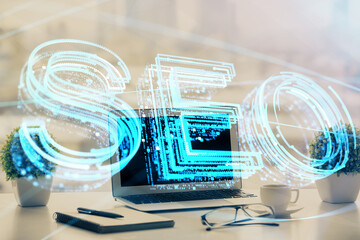 Double exposure of table with computer and seo drawing hologram. Search optimization concept.
