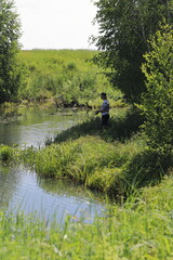a man fishing on the river, a fisherman on the river Bank stands with a fishing rod in hope